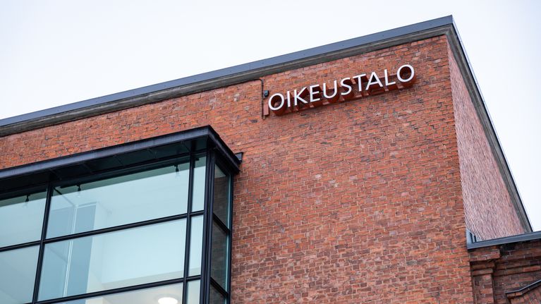 Alaviistosta otettu kuva punatiilisetä oikeustalosta. Rakennuksen seinässä teksti "oikeustalo".