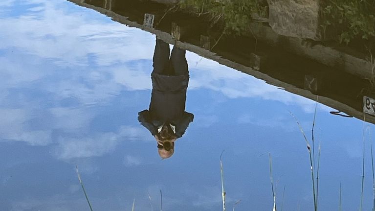 Mies soittaa trumpettia laiturilla veden äärellä kesäisessä maisemassa.