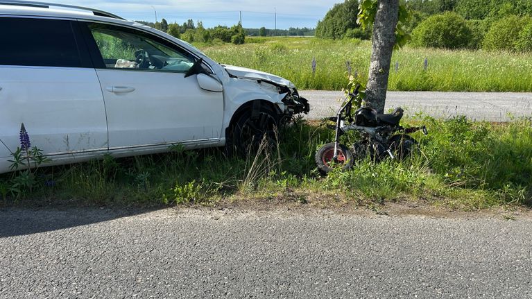 Valkoinen auto ja mopo.