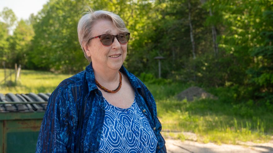 Nainen sinisissä vaatteissa seisoo ulkona.