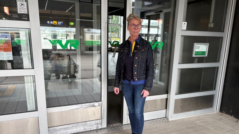 Kirsi Keskinen seisoo asemahallin oven edessä.
