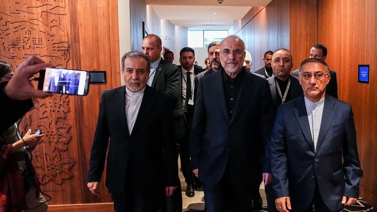 Iranin delegaatio saapuu, vakavat ilmeet, puvut päällä, mutta ei solmioita.