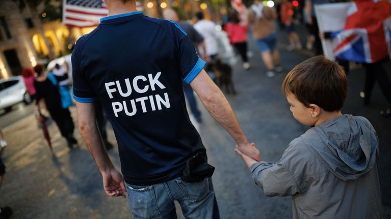 Mies ja lapsi seisovat selin kadulla. Miehen paidassa lukee teksti: "Fuck Putin".