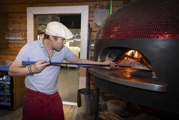 Tuukka Temonen laittaa pizzalapiolla pizzaa uuniin Ravintola Rehtorissa.