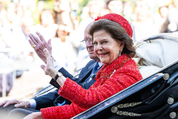 Kuningatar Silvia oli pukeutunut kirkkaanpunaiseen. Kuvassa kuningaspari tervehtii kansalaisia kultahääpäivän kulkueessaan 13.6.2026.