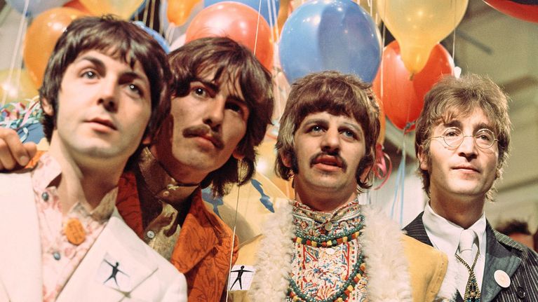 The Beatles poseeraa värikkäissä vaatteissa muutaman ilmapallon edessä.