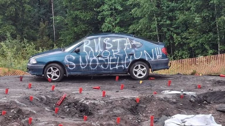 Sininen auto, jonka kylkeen kirjoitettu Riistavuori suojeluun. Taustalla metsä.