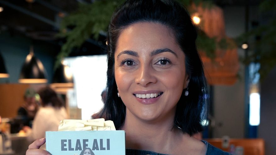 Kirjailija Elaf Ali näyttää iloisena kameralle kirjaansa Sanoitko minulle rakkaus.