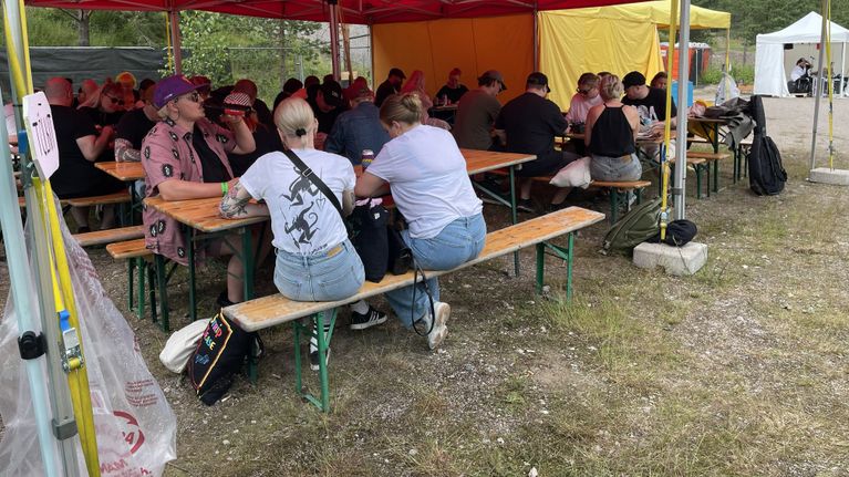 Festarivieraita on kokoontunut telttakatoksen alle varjoon pelaamaan bingoa.