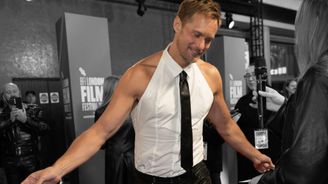 Alexander Skarsgard on pukeutunut valkeaan toppiin joka näyttää hänen olkapäänsä, nahkakravattiin ja nahkahousuihin. Hän tanssahtaa keveästi haastattelijalle ja hymyilee.