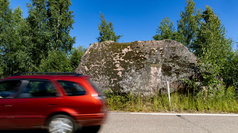 Punainen auto ajamassa pistoolikiven ohi.