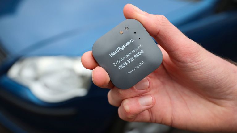 Käsi pitelee pientä autoon kiinnitettävää lisälaitette, jolla seurataan ajokäyttäytymistä.
