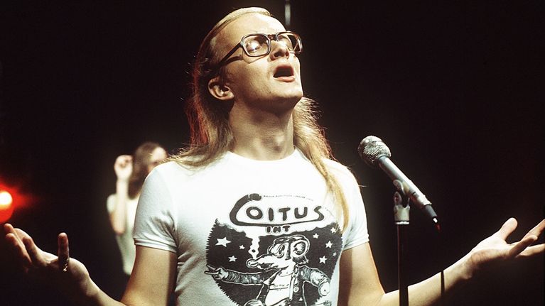 Juice Leskinen nuorempana laulamassa lavalla. Yllään hänellä on valkoinen Coitus Intin t-paita.