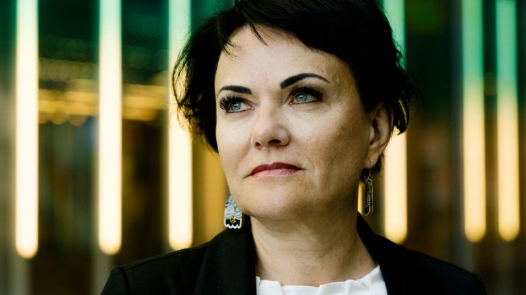 Minna Kivipelto seisoo loisteputkivalojen edessä.