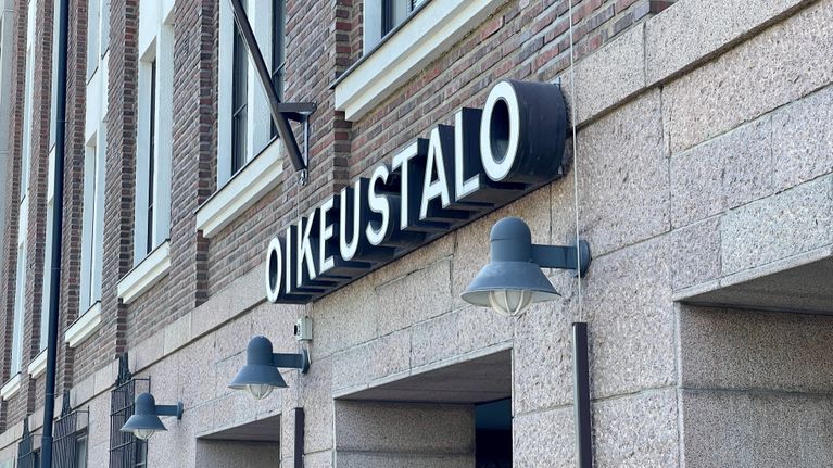 Ison kiviverhoillun talon pääsisäänkäynti. Sisäänkäynnin yläpuolella oikeustalo-kyltt.