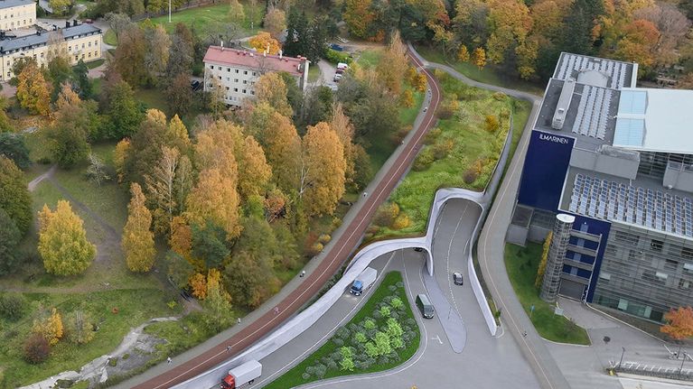 Havainnekuva tunnelin suuaukosta ilmastakäsin katsottuna. Kerrostalon vieressä on tunnelin suuaukko, jonka päällä viherkasveilla kuorrutettu kansi.