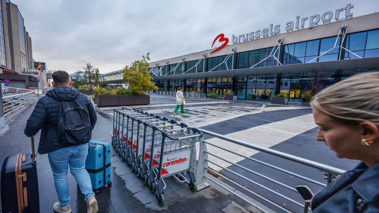 Ihmisiä kävelee matkalaukun kanssa kohti Brysselin lentoaseman sisäänkäyntiä.