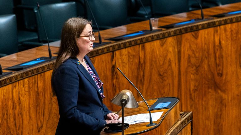 Vihreiden kansanedustaja Inka Hopsu puhumassa vanhuslaista eduskunnan suuressa salissa puhujapöntössä. Taustalla ministereitä.