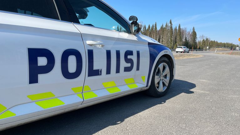 Poliisiauto seisoo tien vieressä.