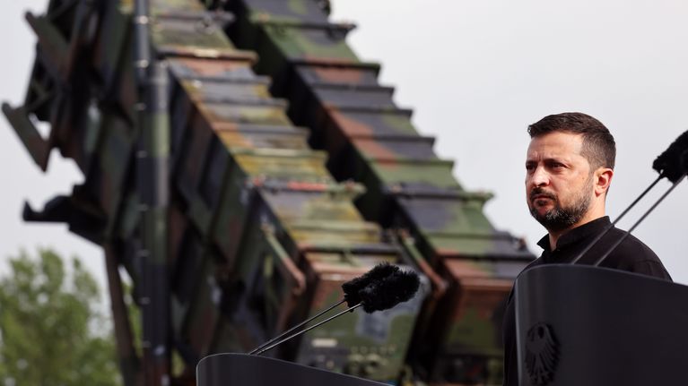 Volodymyr Zelenskyi seisoo puhujakorokkeella takanaan Patriot-ilmatorjuntajärjestelmä.