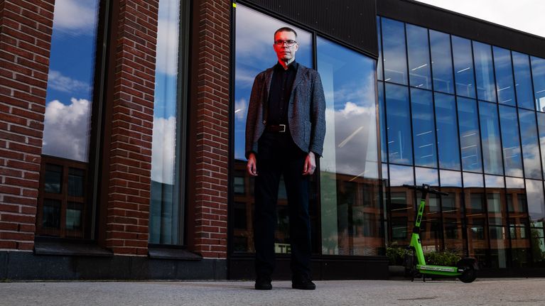 Professori Samuel Kaski poseeraa kameralle Otaniemessä. Kasken kasvoille osuu punainen valo.