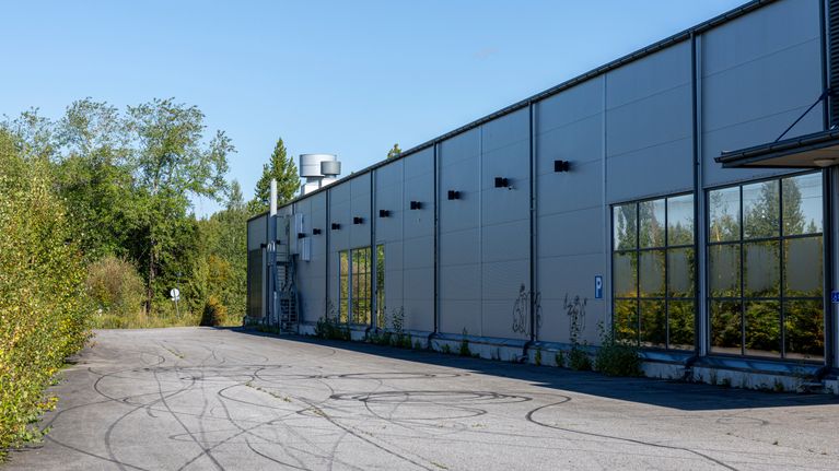 Hylätty teollisuushalli, jonka seinät ovat osittain graffitien peitossa.