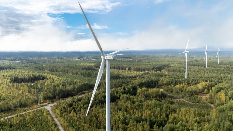 Tuulivoimaloita vihreän metsän keskellä pilvisen taivaan alla symboloimassa kestävää energiaa ja ympäristönsuojelua.