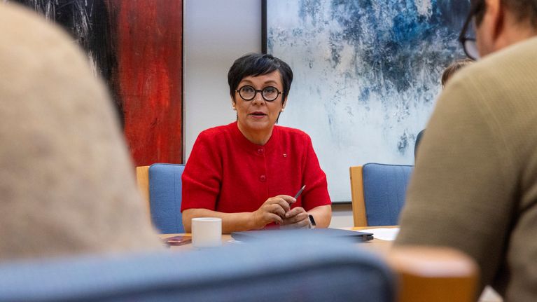 Nainen punaisessa paidassa ja mustissa silmälaseissa.
