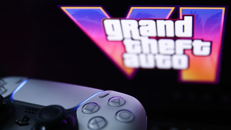 Pelikonsoli ohjain, jonka taustalla lukee grandt theft auto VI.