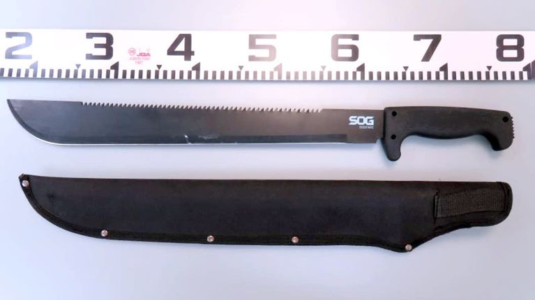 Poliisin haltuunottamia pitkiä machete-veitsiä harmaalla alustalla.
