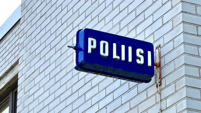 Kangasalan poliisiaseman valkoisen tiilirakennuksen sivu. Seinässä on sininen poliisikyltti.