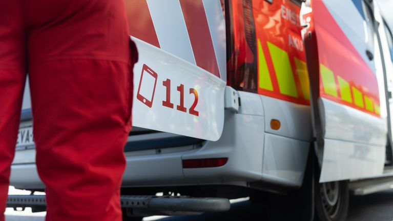 Parkissa oleva ambulanssi ja auton ulkopuoilella oleva ensihoitaja.