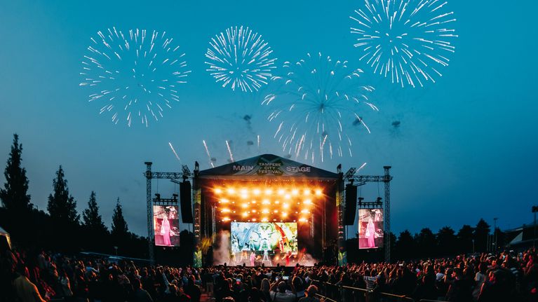 Tampere City Festivalin lavalla esiintyy yhtye, yleisö seuraa esitystä ja taivaalla näkyy ilotulituksia.