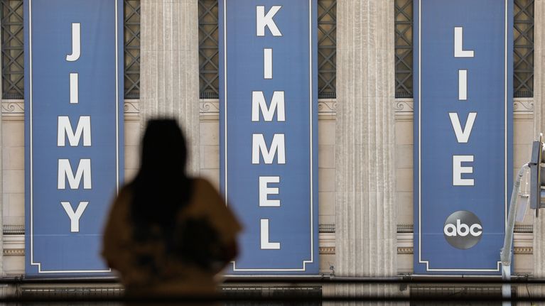 Jimmy Kimmel live kylttejä seinällä, ihmisen siluetti.