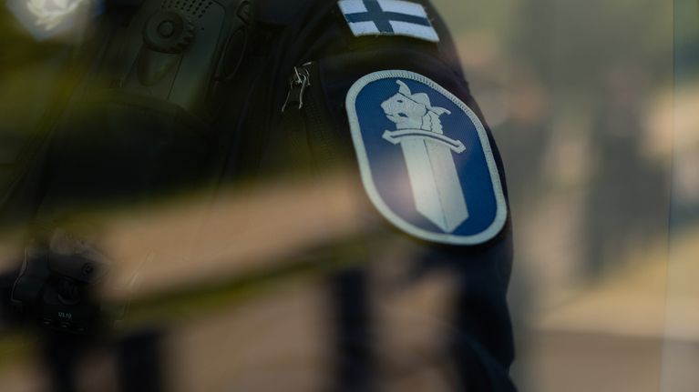 Poliisin hihamerkki auton ikkunan läpi kuvattuna. 
