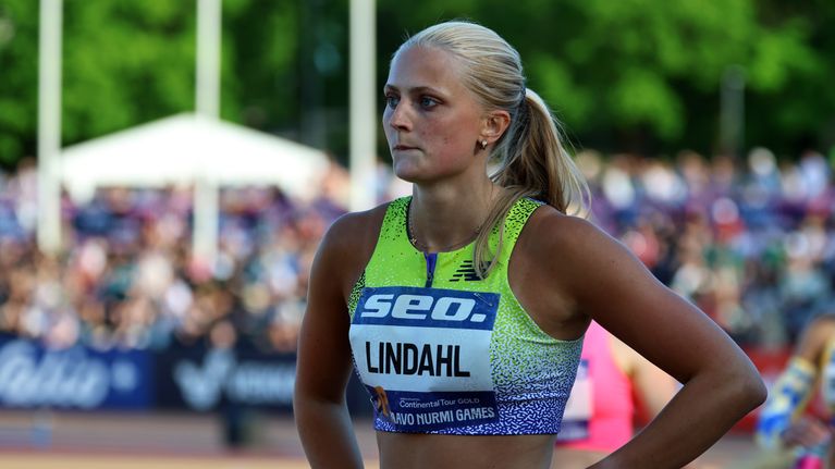 Nainen urheiluvaatteissa juoksuradalla, rintanumerolapussa teksti "LINDAHL" ja "PAAVO NURMI GAMES".