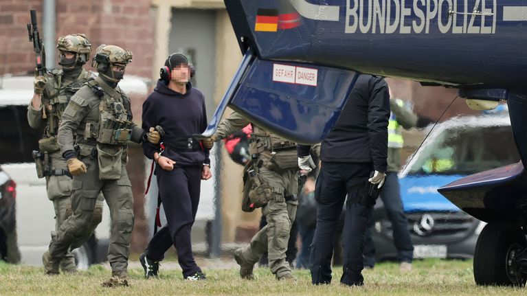 Maastopukuiset vahvasti aseistatuneet miehet taluttavat helikopteriin sinipukuista miestä. Kopterissa lukee Bundespolizei eli Liittovaltion poliisi.
