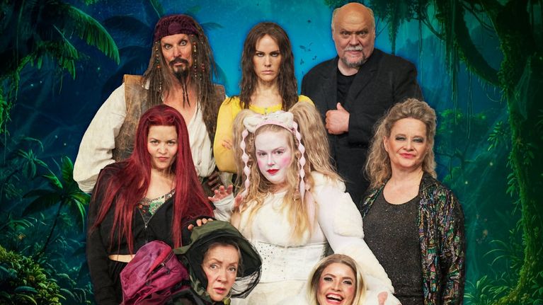 Teatteriesitys: kahdeksan näyttelijää hassuissa hahmoissa ryhmäkuvassa, taustalla näkyy viidakkolavastetta.