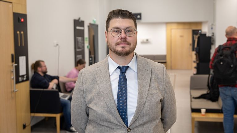 Mies seisoo oikeussalin aulassa.