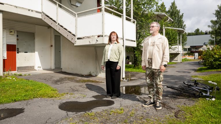 Mies ja nainen seisovat asuinalueen sisäpihalla.