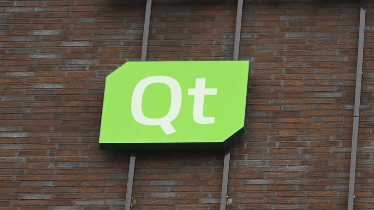 Vihreä kyltti, jossa valkoinen teksti "Qt", on kiinnitetty tiiliseinään.