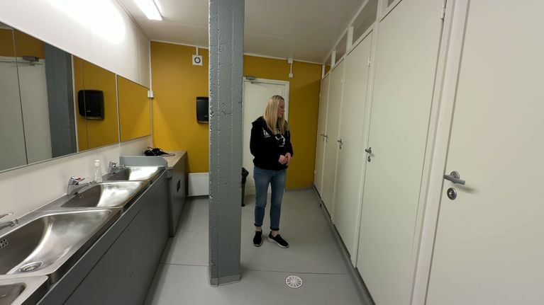 Nainen seisoo tanssilavan naisten wc-tilassa pesualtaiden ja suljettujen wc-koppien edessä.