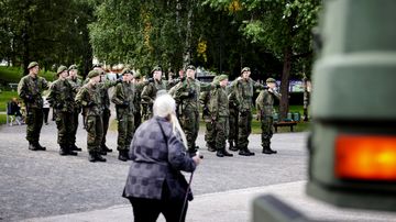 Ryhmä varusmiehiä seisoo rivissä ulkona puistossa.
