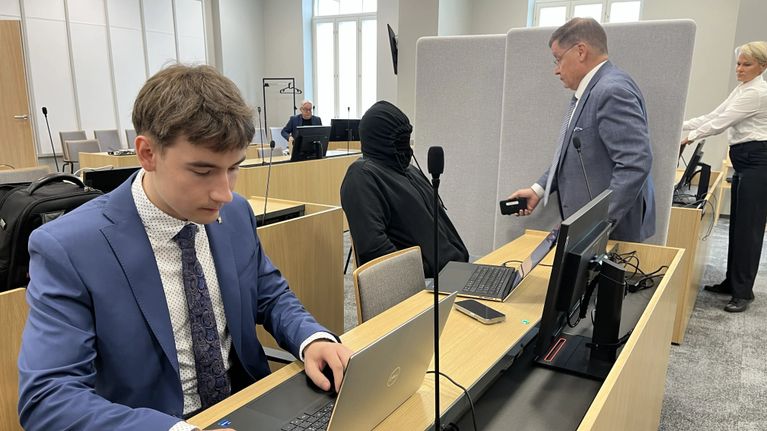 Mika Moring istuu Pohjois-Savon käräjäoikeudessa pukeutuneena mustaan huppariin. Hänen vieressään seisoo puolustusasianajaja Kaarle Gummerus