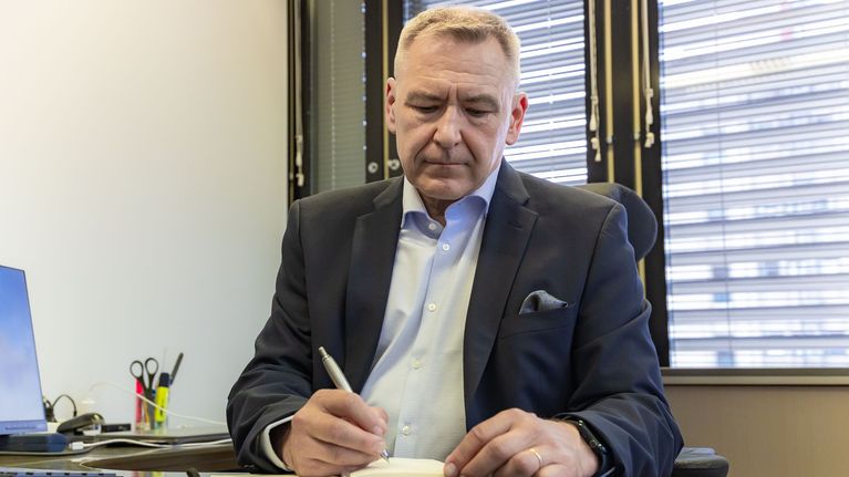 Valtakunnanvouti Veikko Minkkinen työpöytänsä ääressä kirjoittaa kynällä muistikirjaan.