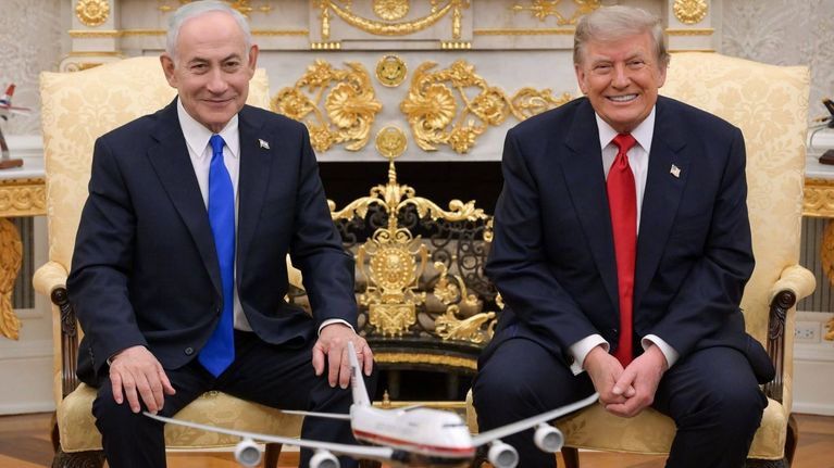Benjamin Netanyahu och Donald Trump sitter bredvid varandra i Vita huset och ler mot kameran.