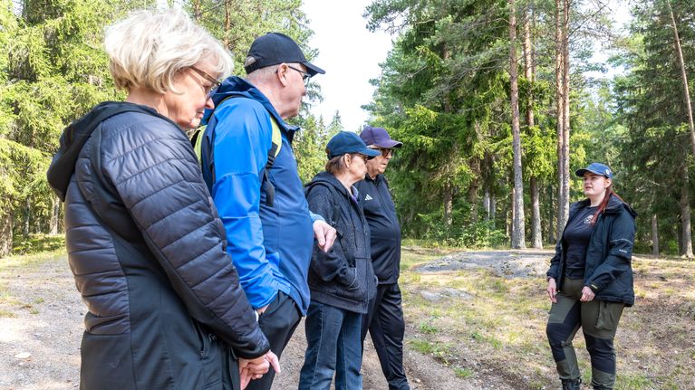 Kaksi pariskuntaa seisoo polulla ja juttelee reitistömestarin kanssa.