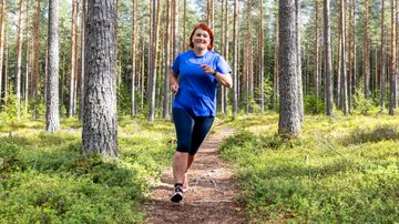 Nainen juoksee polulla männikössä.