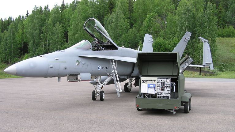 Jäähdytyskaasugeneraattori hornetin edessä, taustalla metsää.