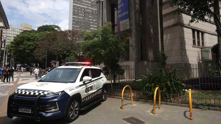 Poliisiauto on pysäköitynä kirjaston eteen Brasilian São Paulossa, taustalla näkyy puu ja useita korkeita rakennuksia.